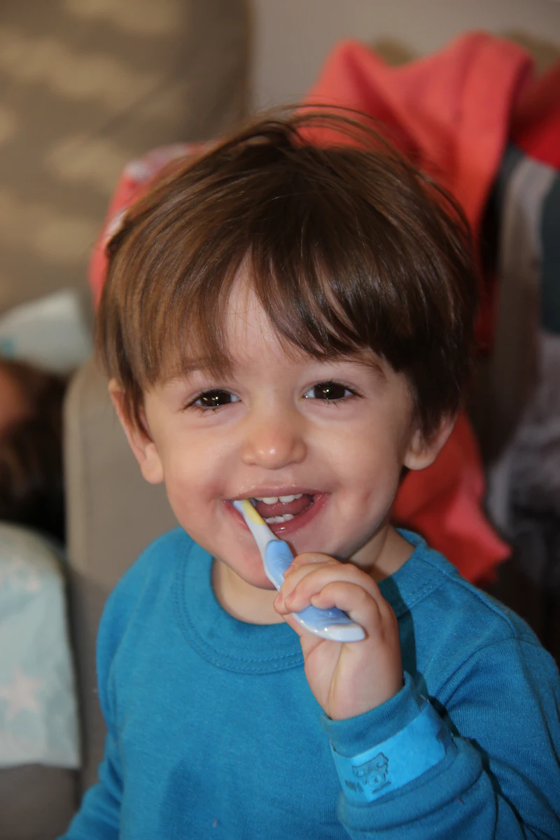 A smiling little boy brushing his teeth